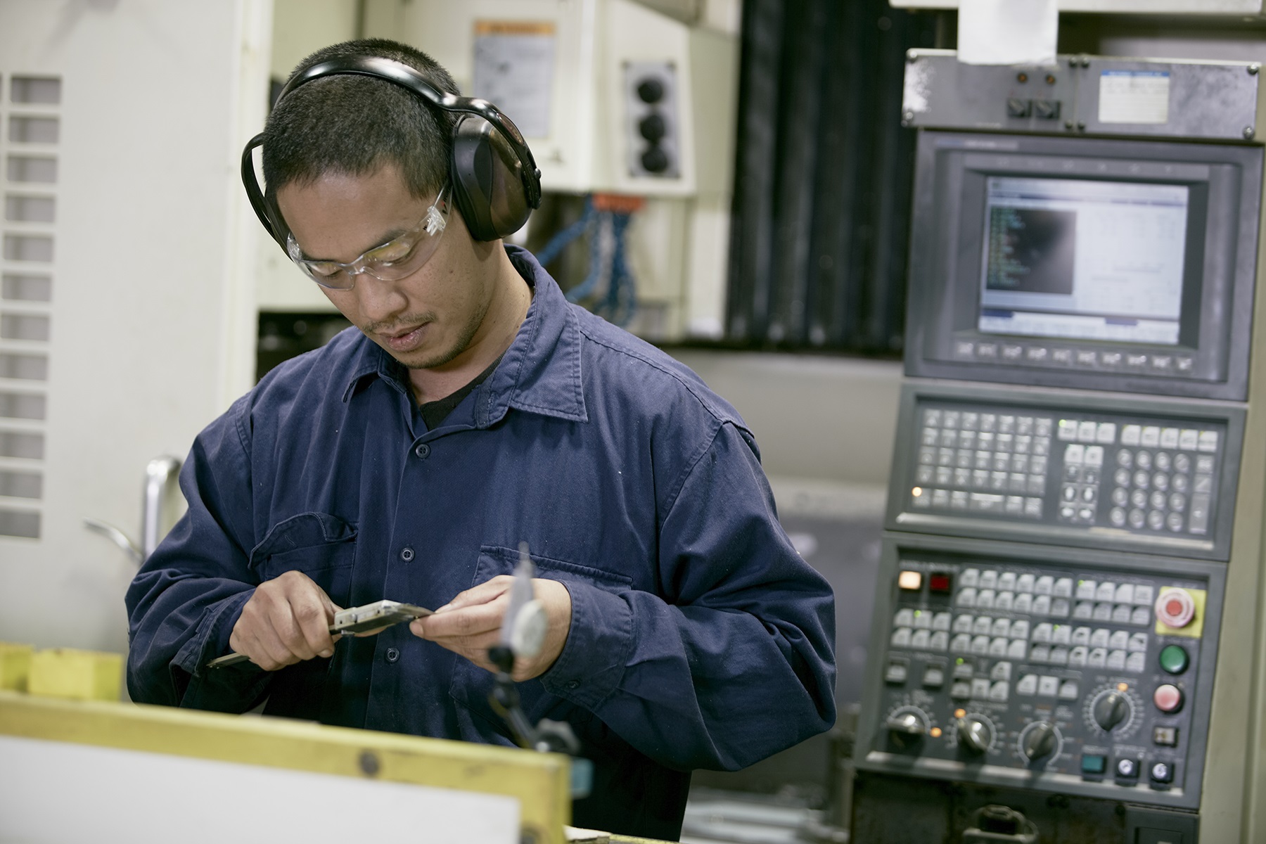 Image of a man working with his hands with electronic equipment behind him. 