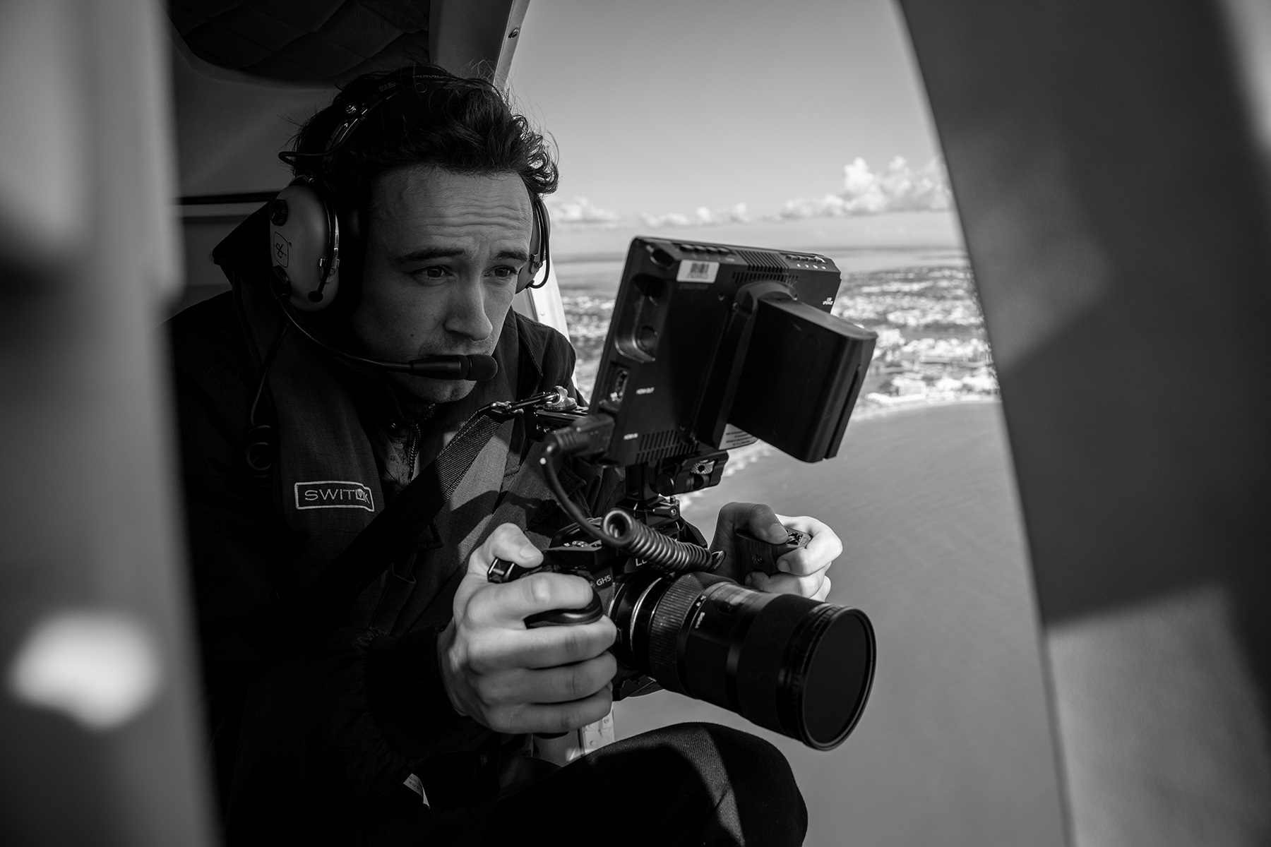 Photo of Laundon Peacock, owner of LP Visuals,  capturing aerial footage from a helicopter.