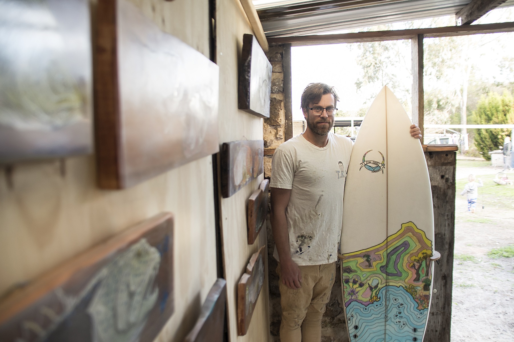 Photo of Pat McCarthy holding one of his hand-shaped custom surfboards.