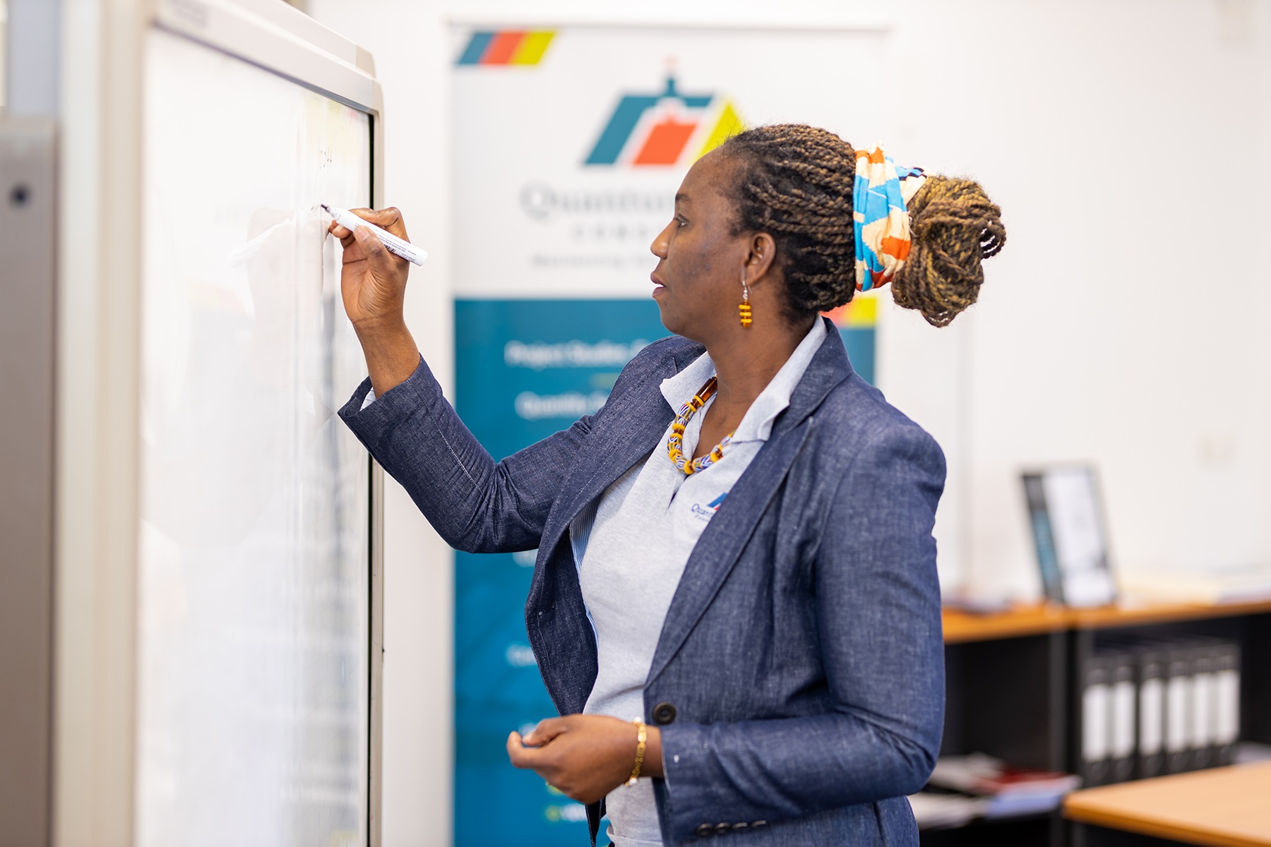 Photo of Quantum Phases Consortium owner Adwoa Abban writing on a whiteboard.