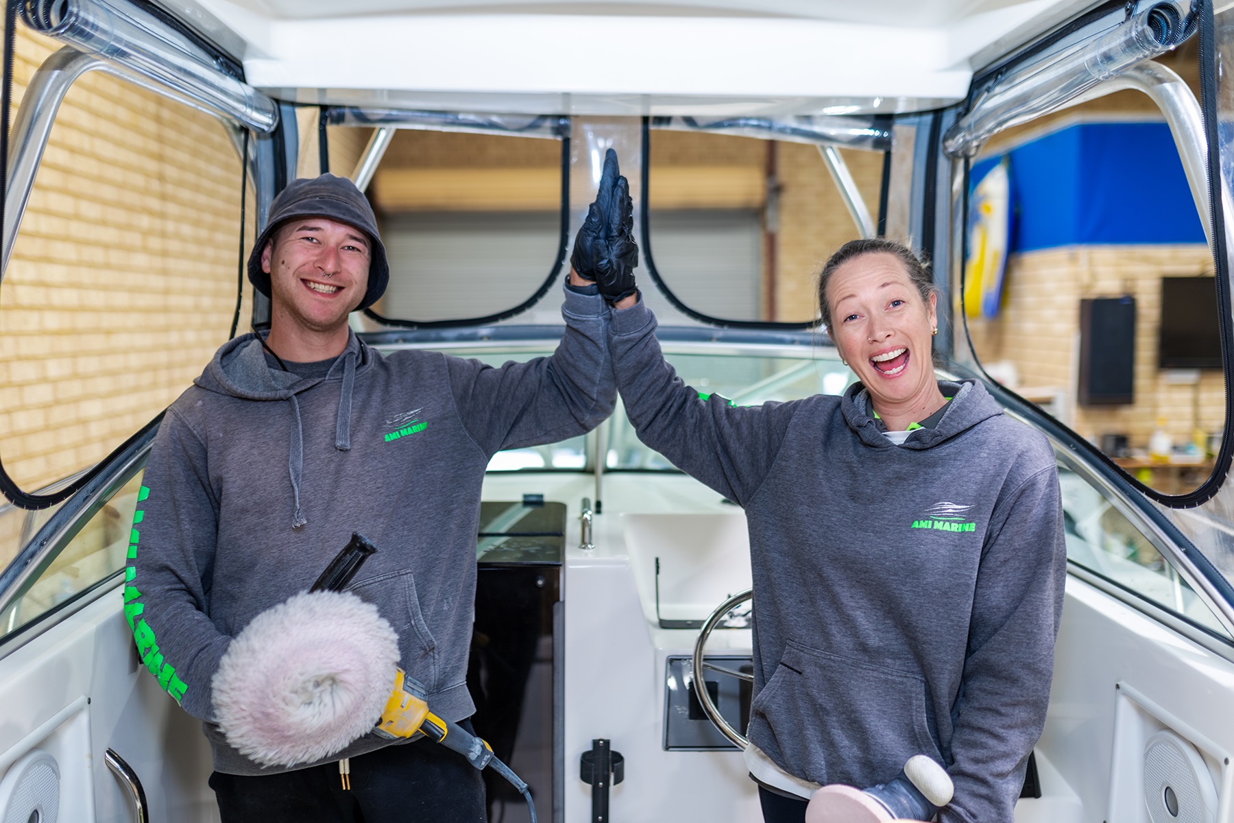 Photo of Ami Hacket, owner of Ami Marine, with her brother Angus who works in the business with her. They are high fiving on a boat.