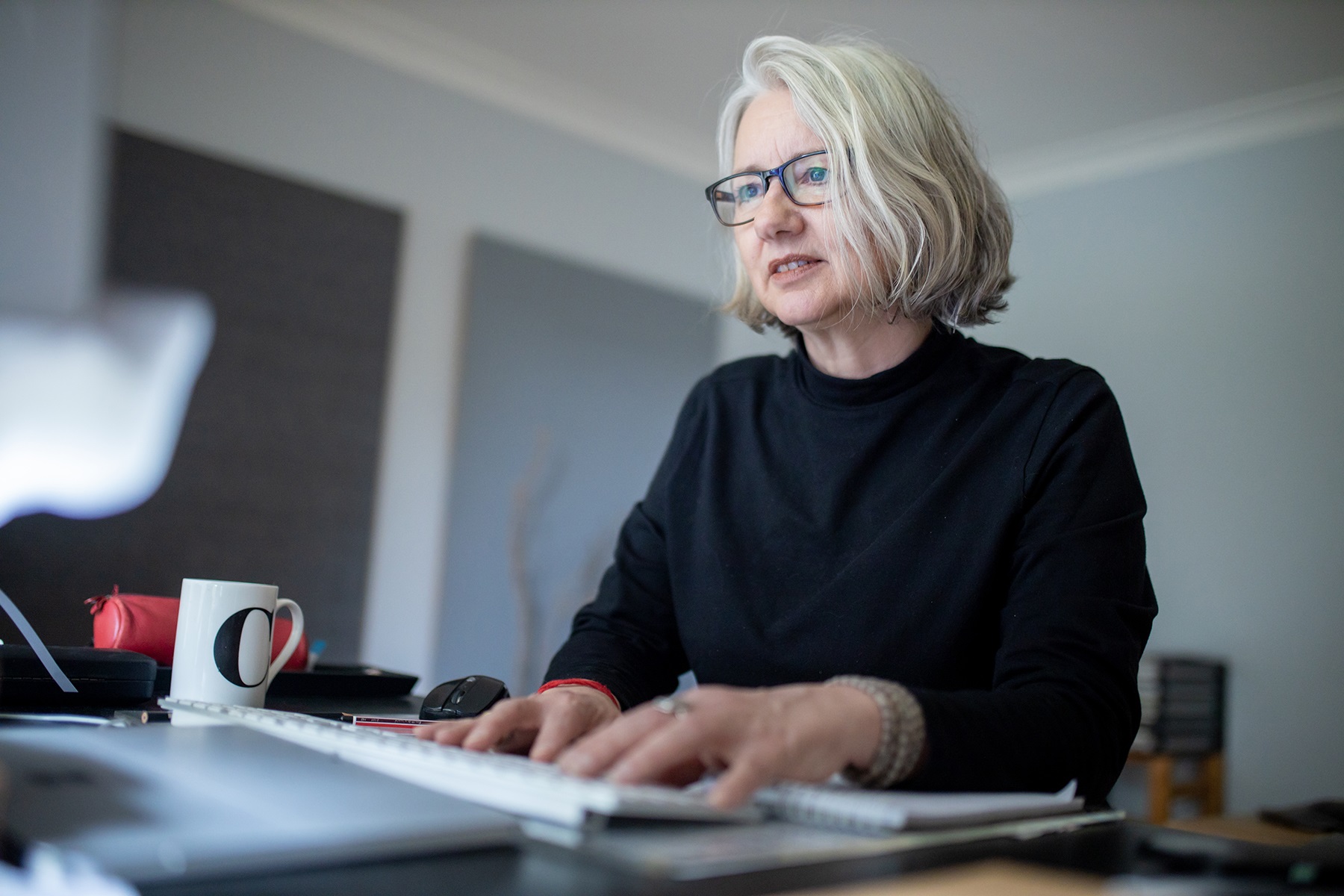 Photo of a female business owner typing on a keyboard in her home office.