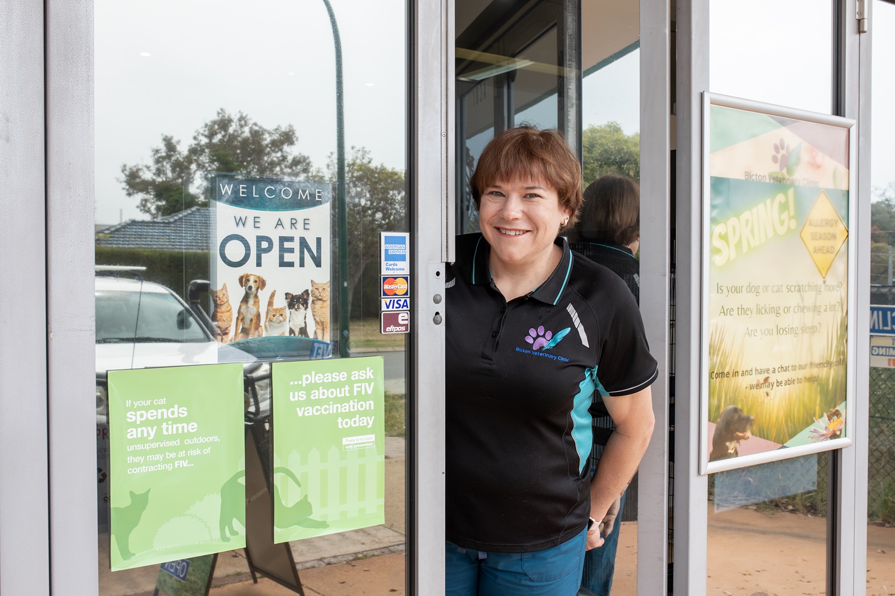 Photo of a female small business owner standing in the doorway to her business.