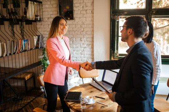Photo of a man and woman shaking hands in an office.